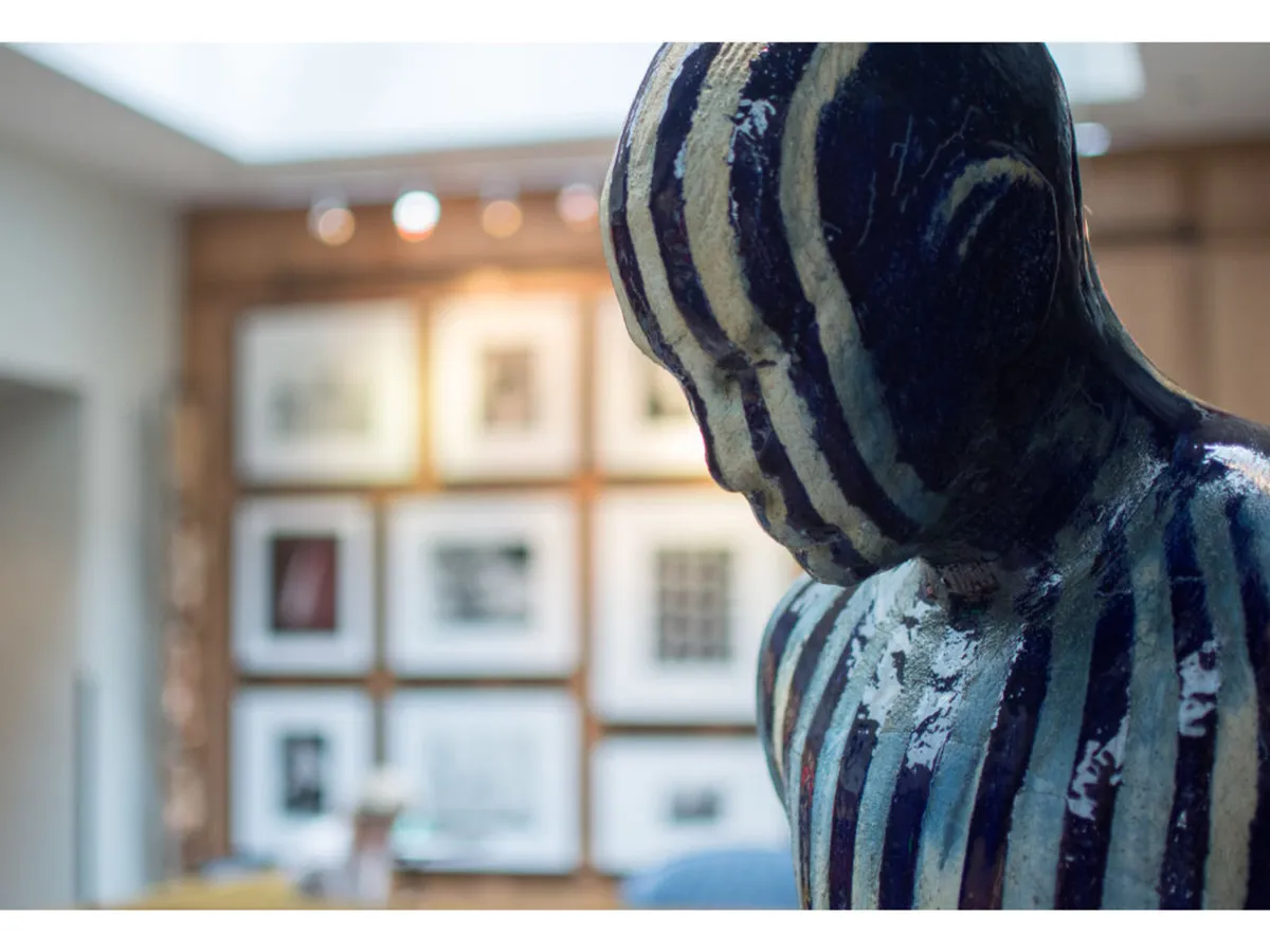A thoughtfully arranged interior space featuring a striking striped sculpture and a gallery wall adorned with framed art. The area invites quiet reflection and creative inspiration, with gentle lighting and comfortable seating that encourage introspection.