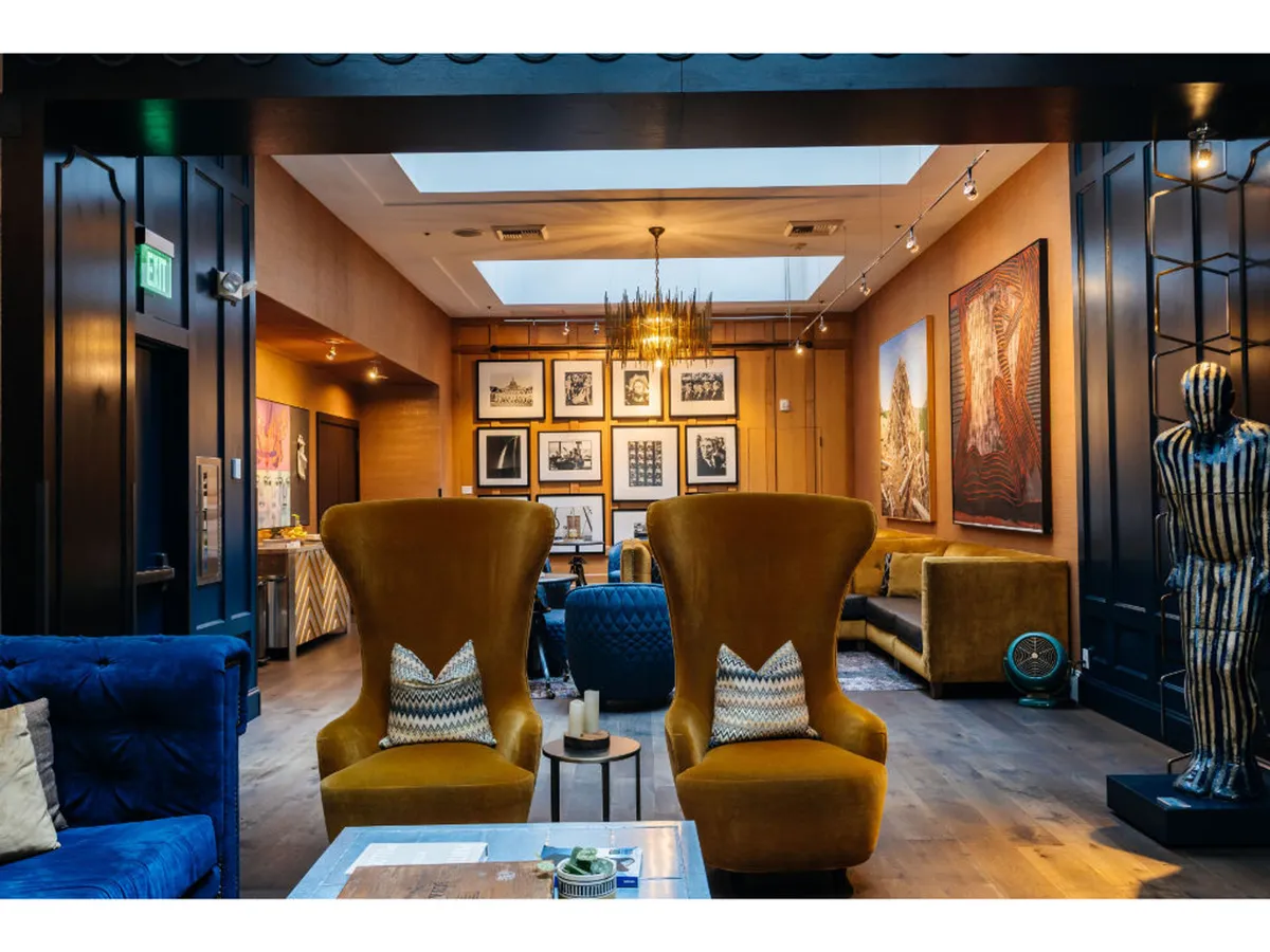 A creative lounge area featuring bold yellow armchairs, a unique sculpture, and vibrant artwork on the walls. The arrangement encourages guests to relax, socialize, or immerse themselves in the artistic ambiance.