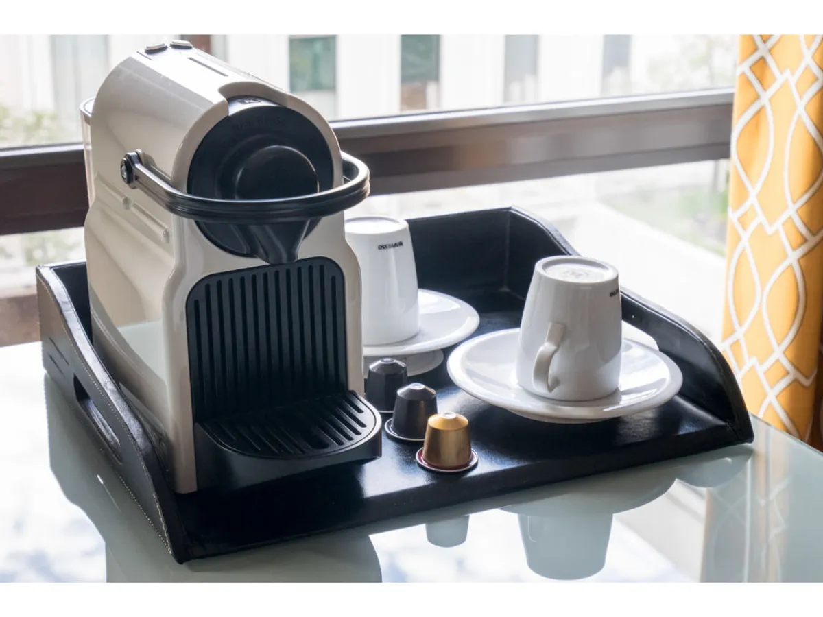 A refined in-room coffee station featuring a Nespresso machine, coffee cups, and a tray of capsules, set beside a window. The setup invites guests to enjoy premium coffee or tea in a cozy, private ambiance, reflecting thoughtful modern amenities.