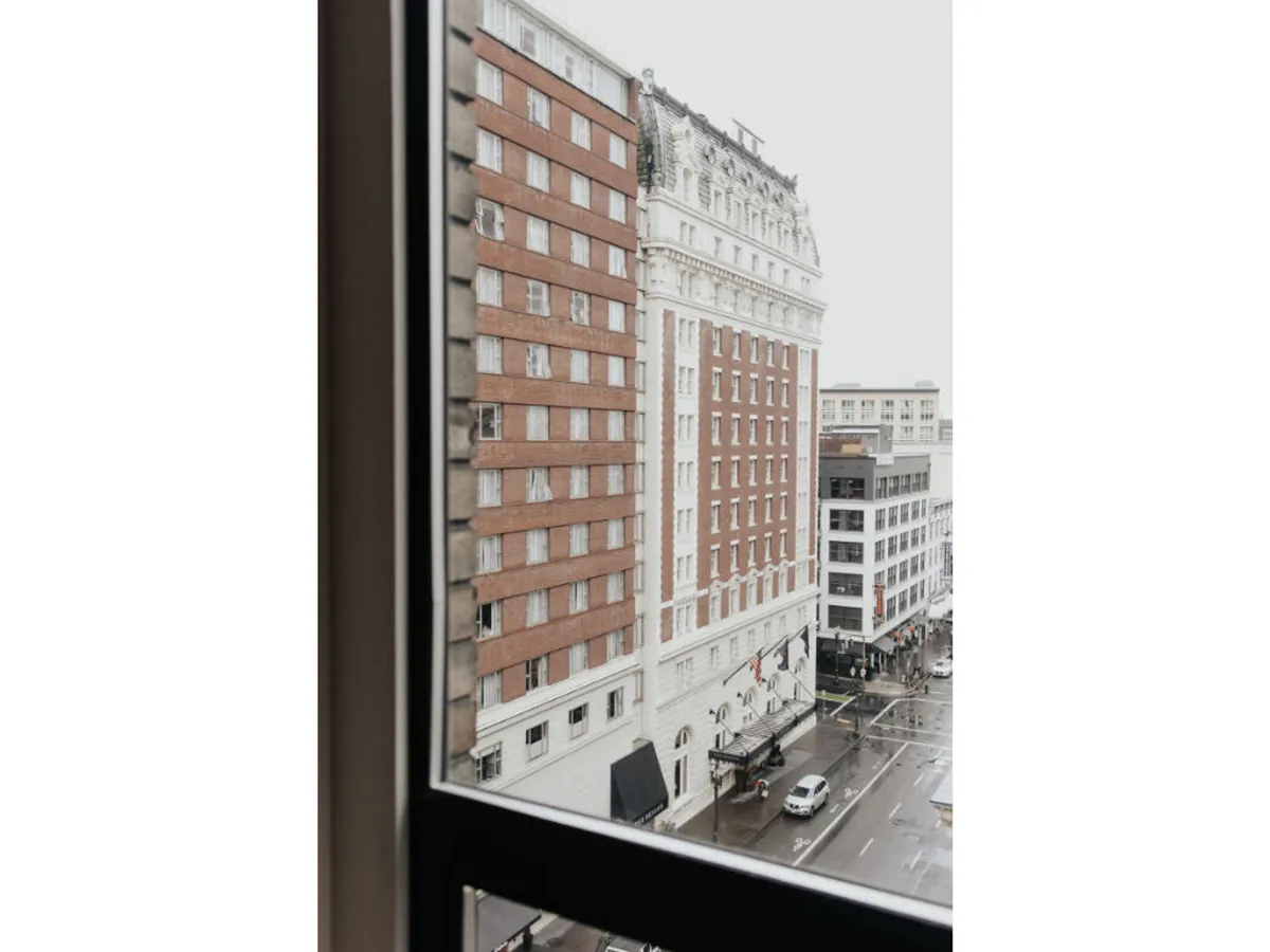A moody, atmospheric city view showing historic Portland buildings, rain-slicked streets, and passing vehicles. The image evokes urban exploration and showcases the juxtaposition of the city’s old and new architectural elements.